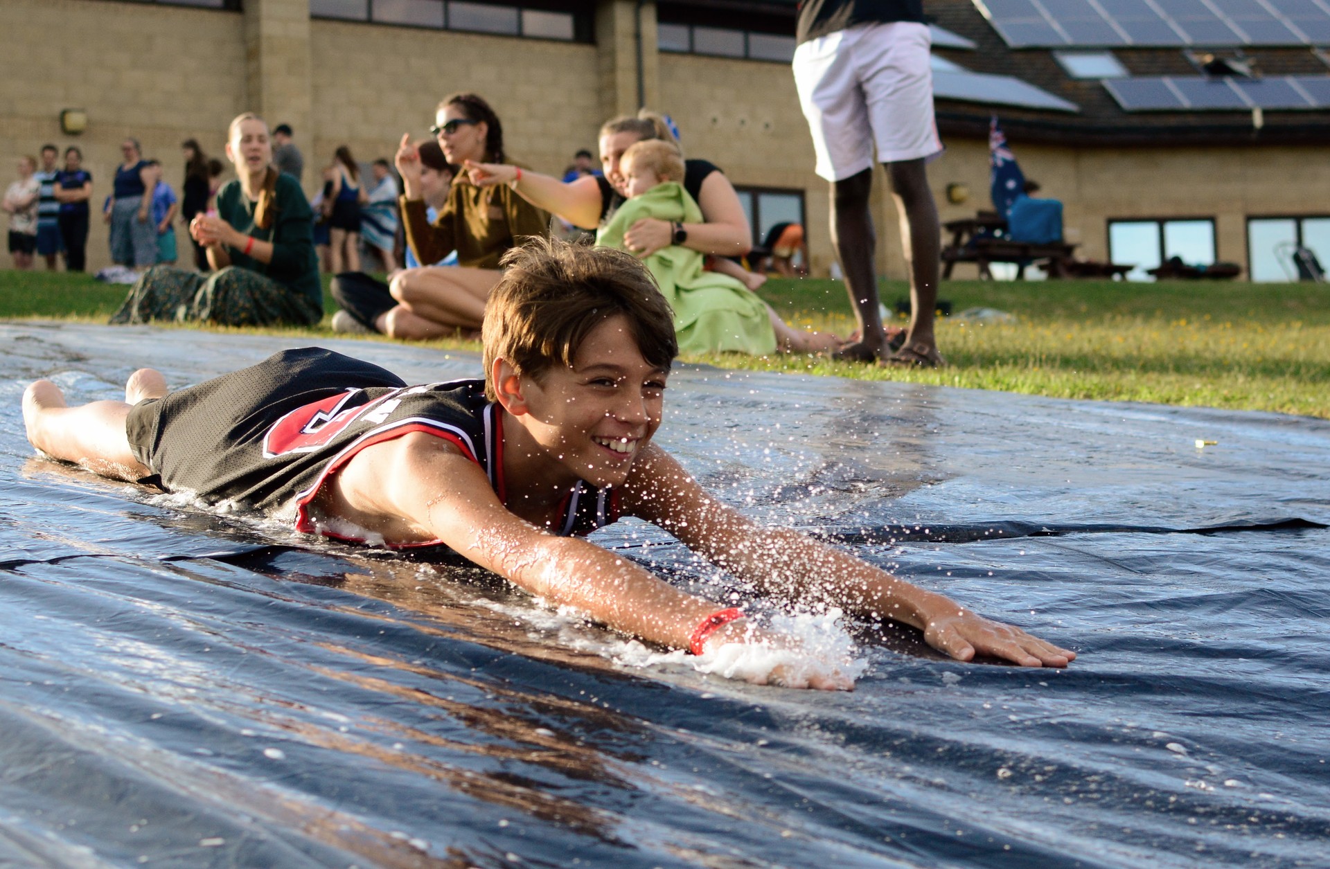 A camper enjoying the water games, sliding down a hill.